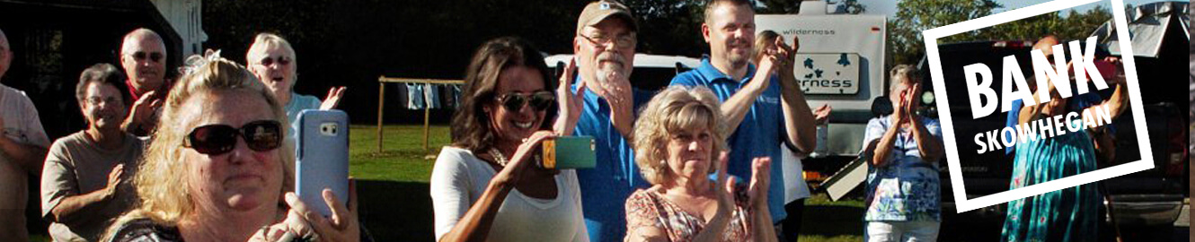 A group of people taking pictures with their smartphones, with the text "Bank Skowhegan"